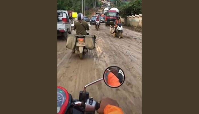 Seorang Pengendara Motor Melintasi Jalan Becek di Kawasan IKN